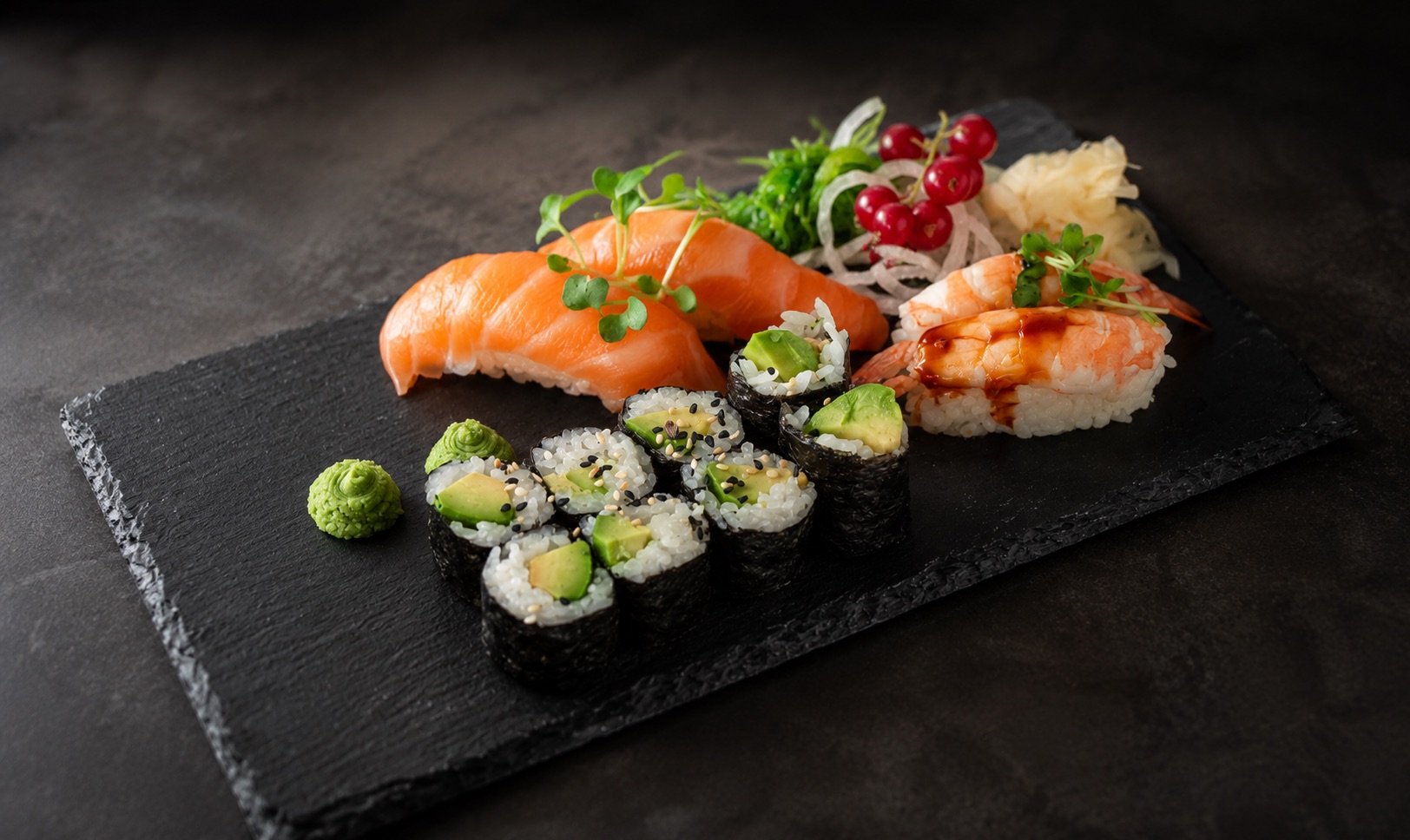 Sushi-Platte mit Lachs-Nigiri, Maki und Garnelen auf schwarzem Schieferbrett