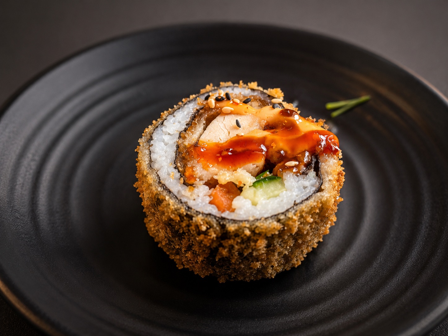 Knusprig frittierte Tempura-Rolle mit Soße auf schwarzem Teller